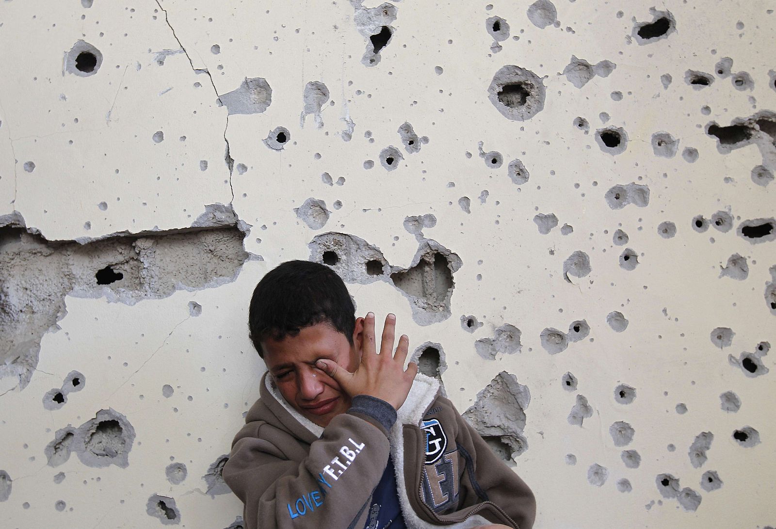 Un niño palestino llora junto a su casa, dañada por un ataque aéreo en Beit Lahia, norte de Gaza
