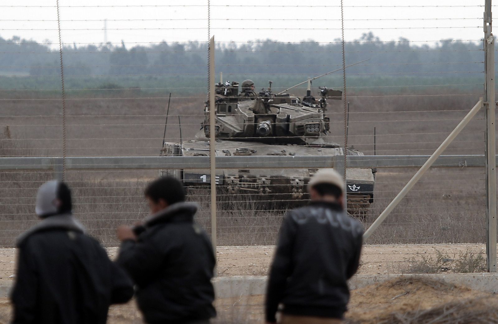 Palestinos frente a la verja que separa Gaza de Israel. Al otro lado, un tanque del Ejército hebreo