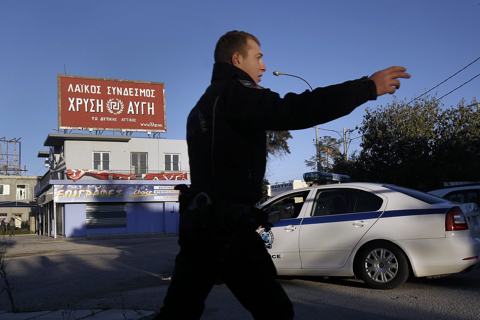 Un policía griego dirige el tráfico frente a la sede del partido neonazi Amanecer Dorado en Aspropyrgos, atacada con un artefacto explosivo