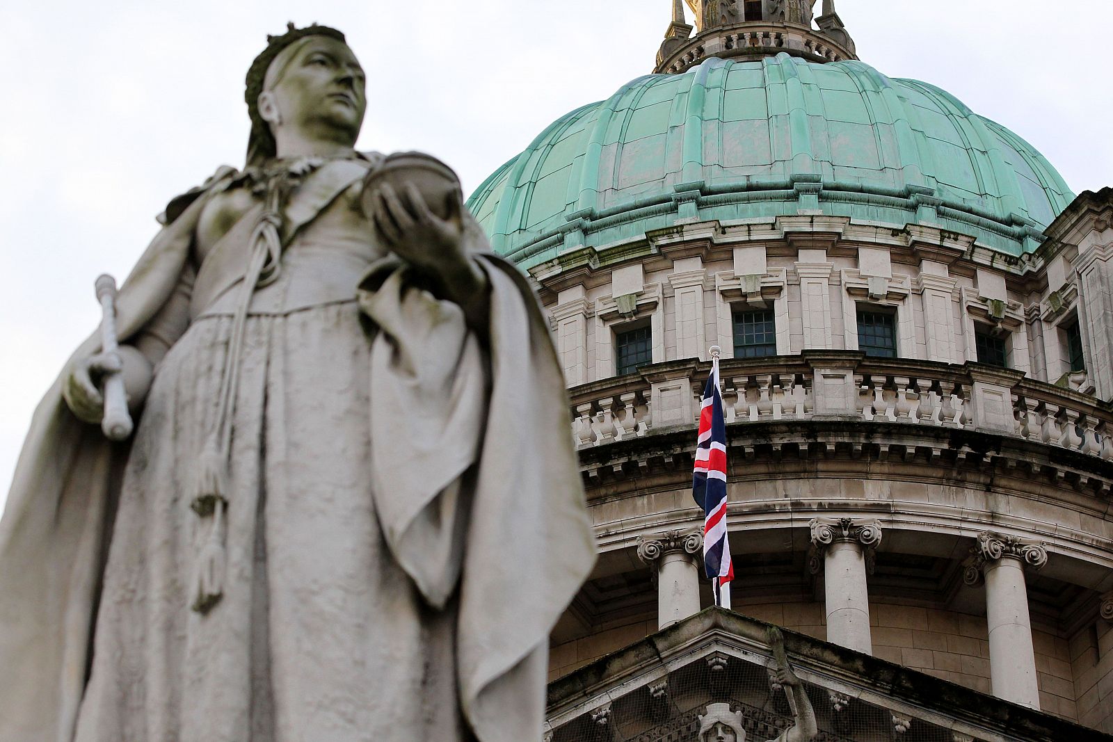 Una estatua de la reina Victoria aparece en primer plano frente al ayuntamiento de Belfast, donde ondea la Union Jack, la bandera británica