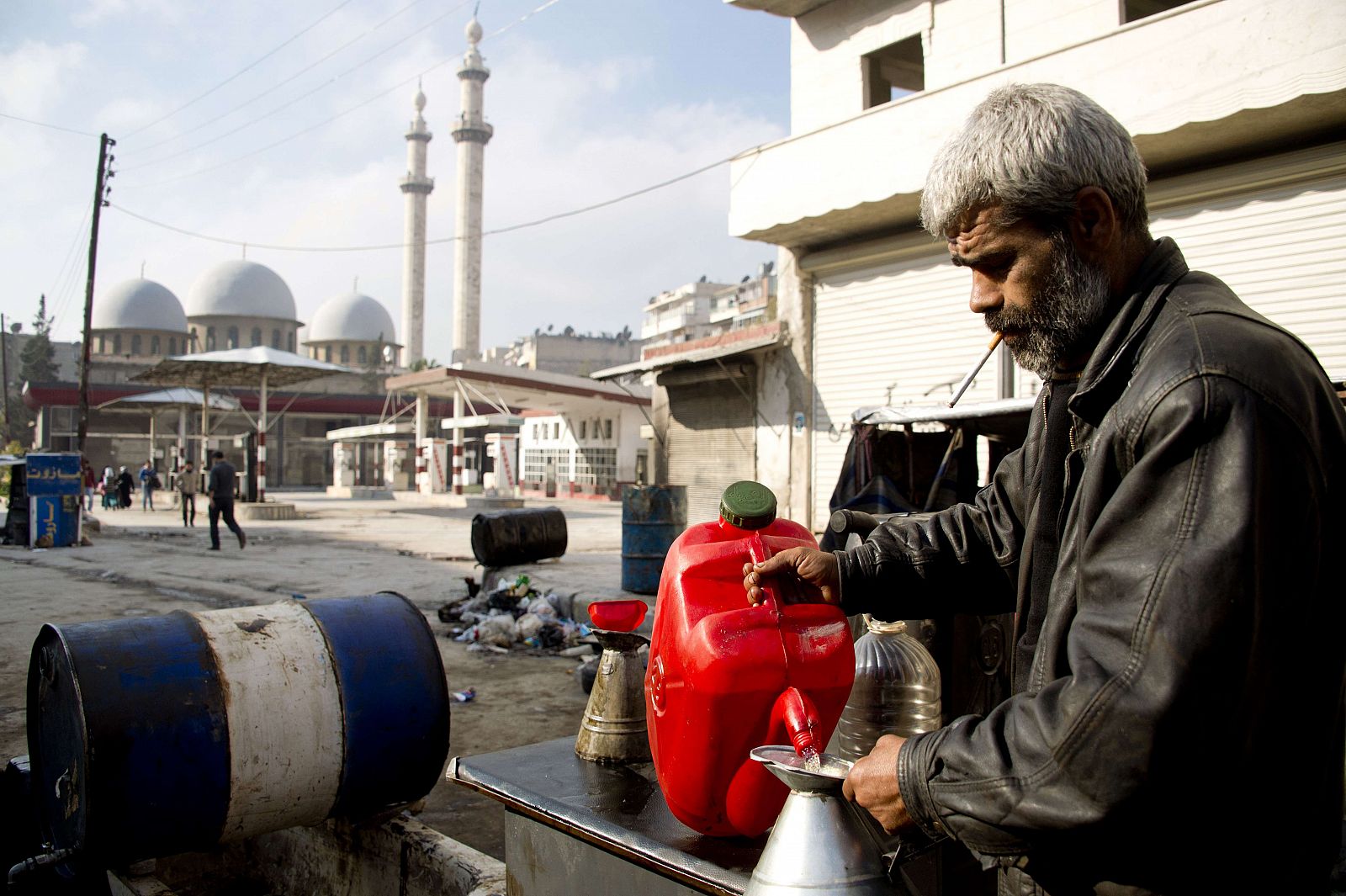 Este hombre ha montado un puesto de venta de carburante entre las ruinas de una gasolinera destrozada por un bombardeo en Alepo.