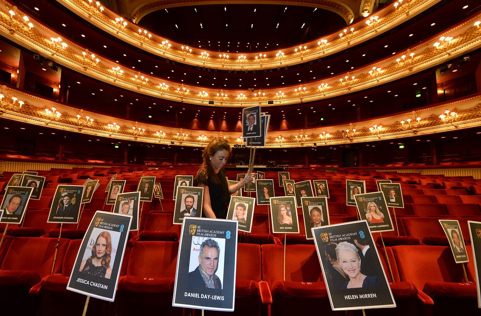 Production staff member Rosie Wiseman places position markers representing guests ahead of the BAFTA awards at the Royal Opera House in central London