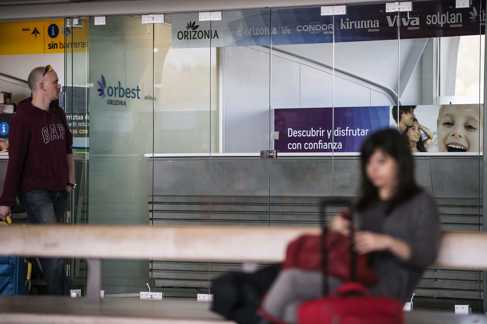 Dos pasajeros delante de la oficina de la aerolínea Orbest del grupo Orizonia en el aeropuerto de Bilbao