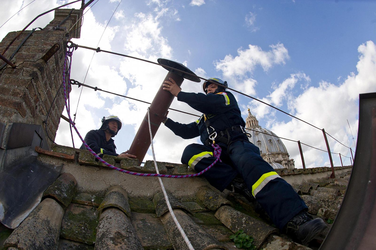 Dos bomberos colocan la chimenea por la que saldrá la "fumata blanca" que anunciará al mundo que la Iglesia Católica tiene nuevo papa, en el techo de la Capilla Sixtina.