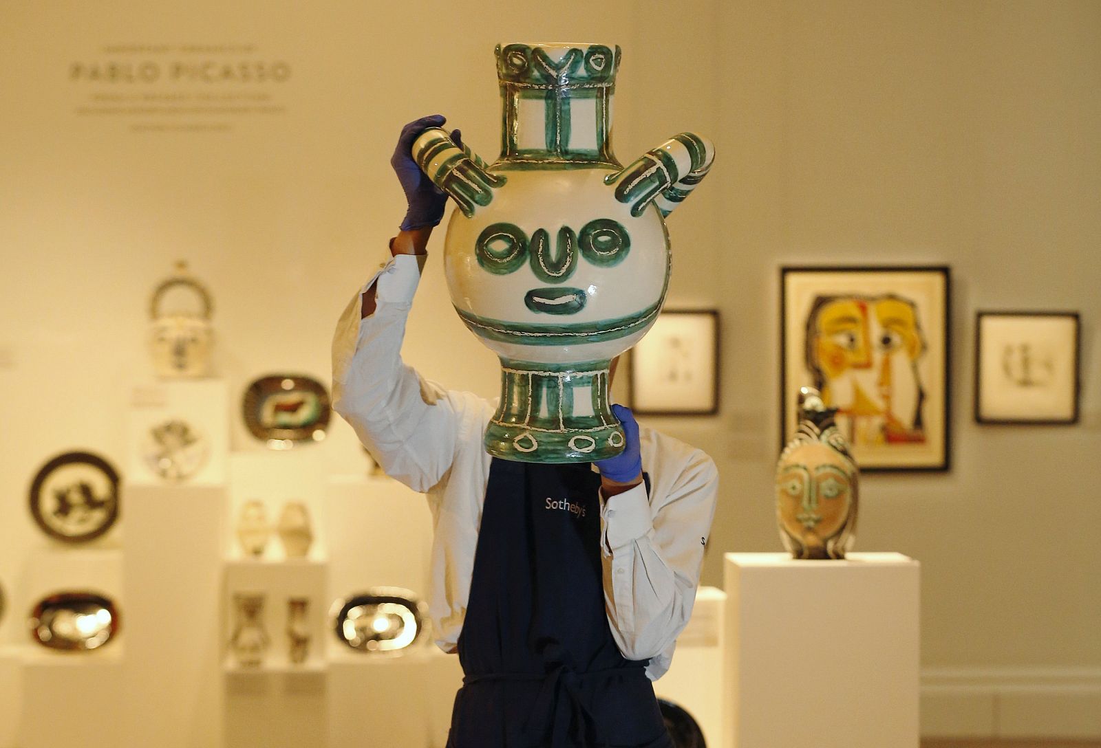 A Sotheby's worker poses with "Vase Gros Oiseau Vert"  by Pablo Picasso, at Sotheby's in London