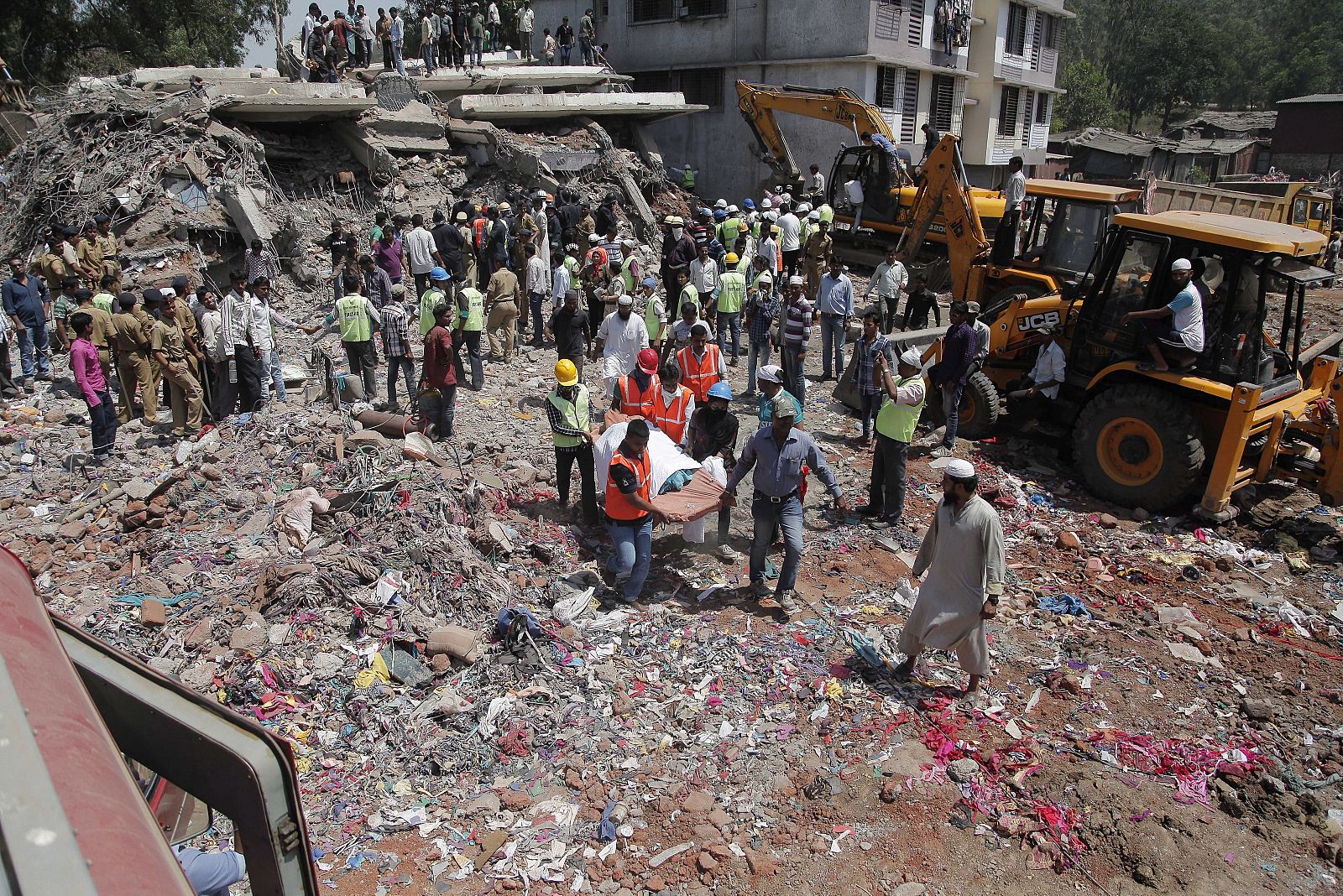 Miembros de los servicios de emergencia transportan el cadáver de una de las víctimas tras derrumbarse un inmueble de construcción ilegal en la localidad de Thane, próxima a Bombay.