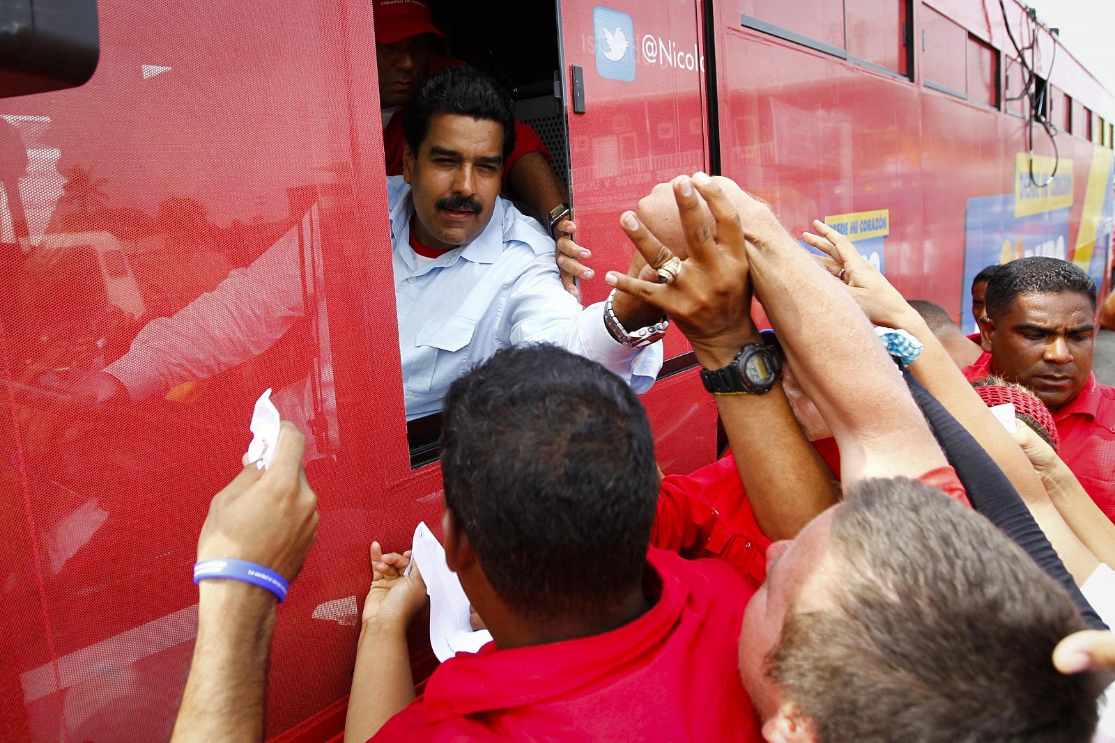 Nicolás Maduro saluda desde la ventanilla del conductor del autobús de su campaña.