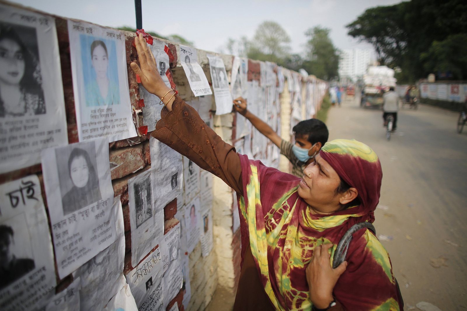 Una mujer comprueba la lista de nombres de desaparecidos por el derrumbe del edificio en Bangladesh