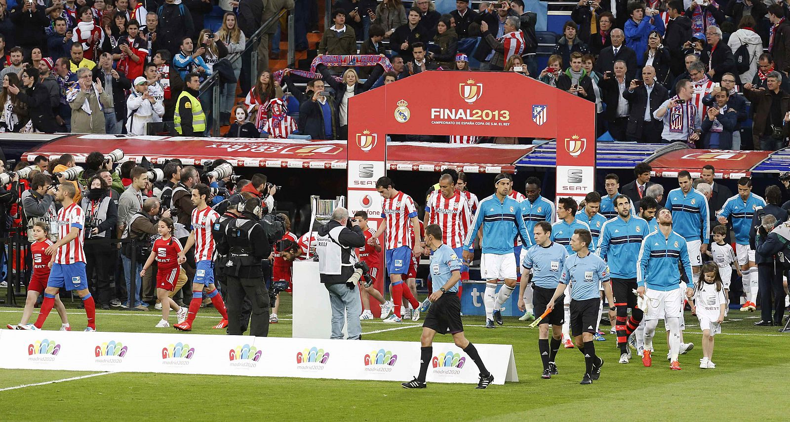 Los jugadores de Real Madrid y Atlético de Madrid salen del túnel de vestuarios flanqueando al trofeo de Copa