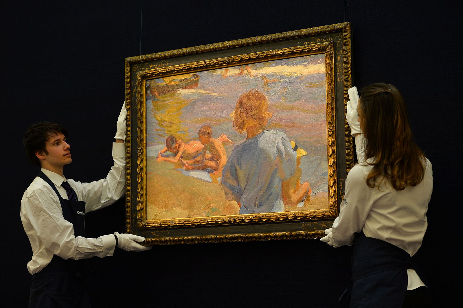 Los empleados de la casa de subastas transportan 'Niños en la playa' de Joaquín Sorolla.