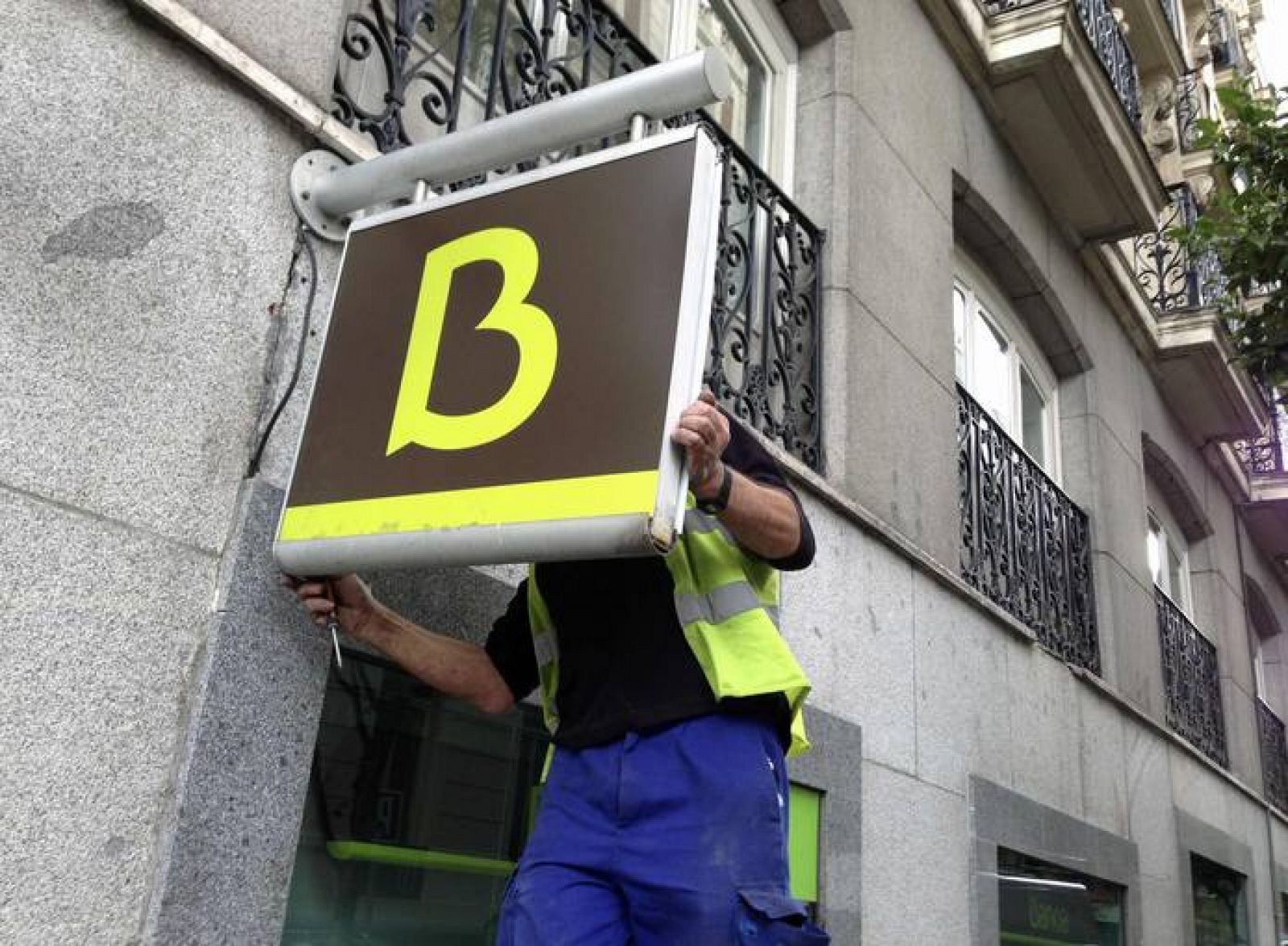 Un hombre coloca el logo en una sucursal de Bankia