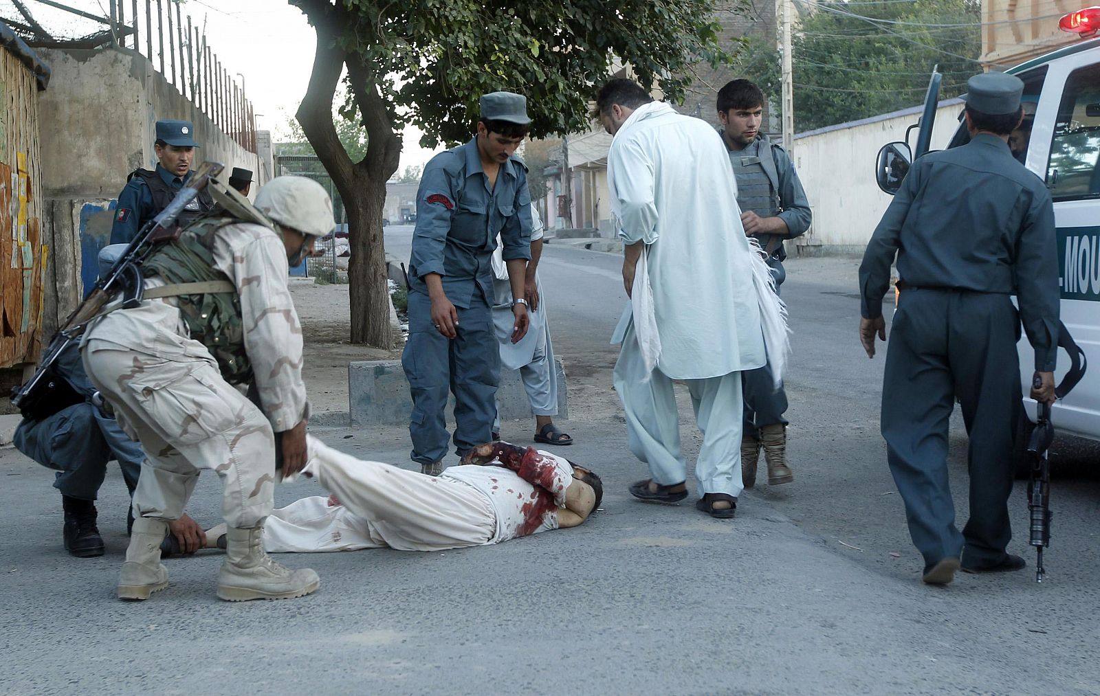Afghan policemen help a victim from the site of attack in Jalalabad province