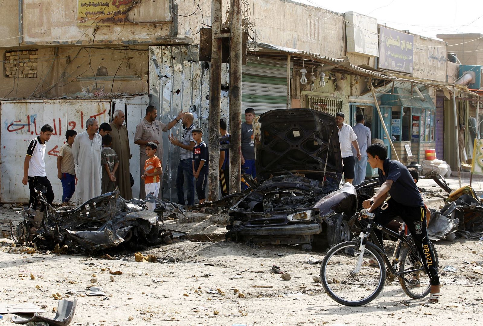Un grupo de iraquíes se concentran en torno al escenario de uno de los atentados que golpearon Bagdad, en Al Huseiniya.