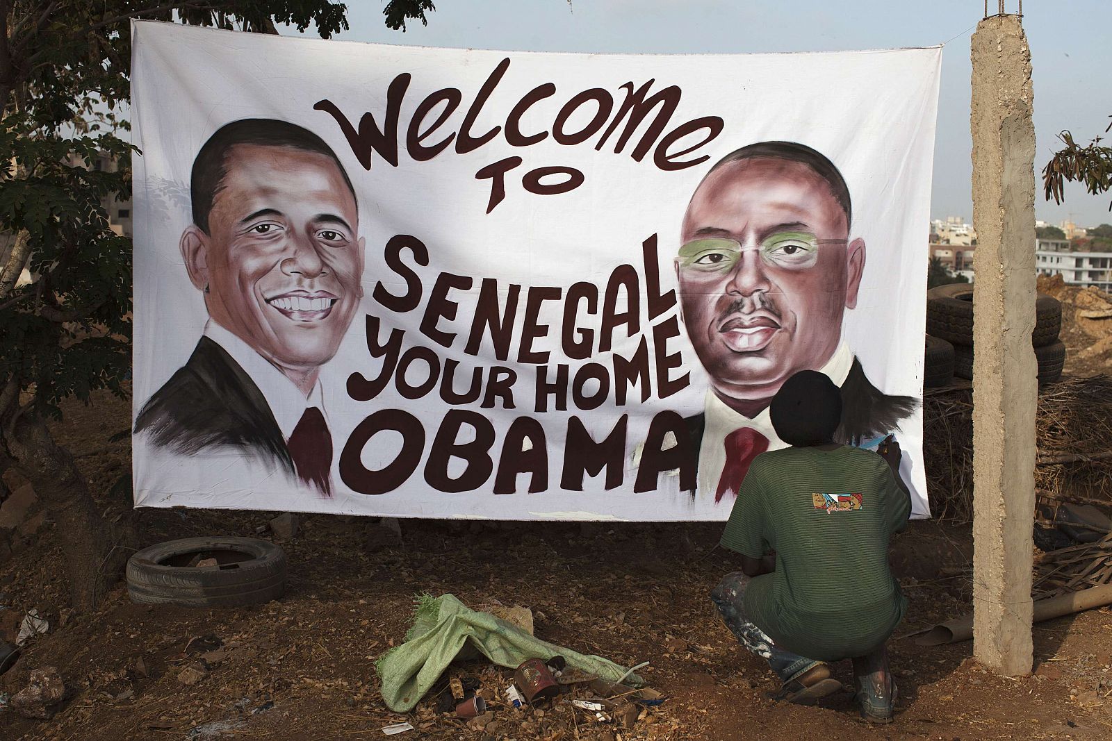 Ouzin, artista plástico, pone el toque final en Dakar a un cartel que da la bienvenida a Obama a Senegal