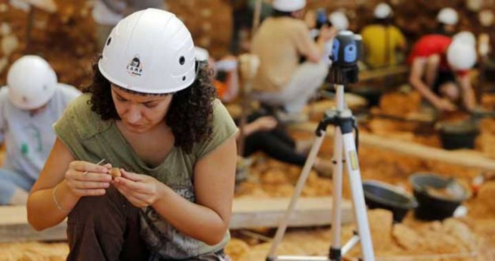 Una joven examina un fragmento de roca en las excavaciones de verano en el yacimiento de Atapuerca.