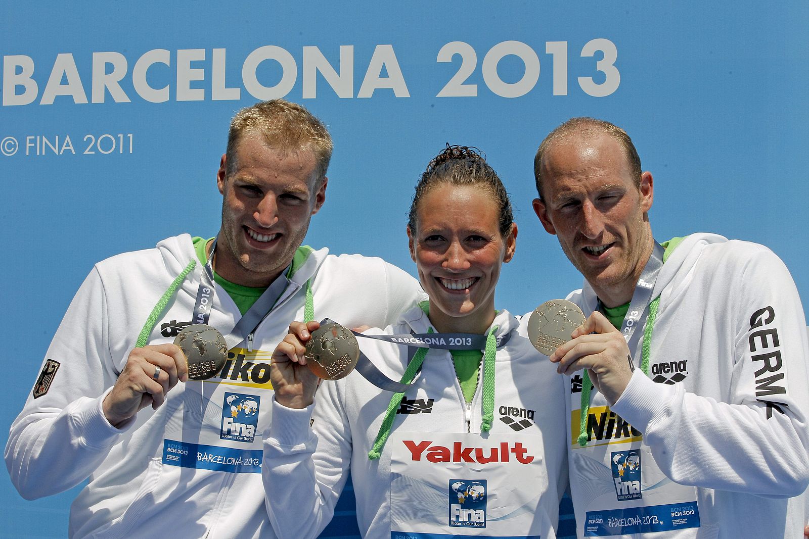 El equipo alemán formado por Christian Reichert, Isabelle Harle y Thomas Lurz, muestran la medalla de oro.