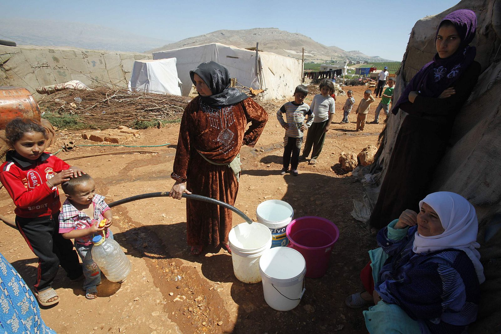 Refugiados sirios llenan baldes con agua en un campamento improvisado para los refugiados en Kfar Zabad en el valle de Bekaa, a pocos kilómetros de la frontera con Siria.