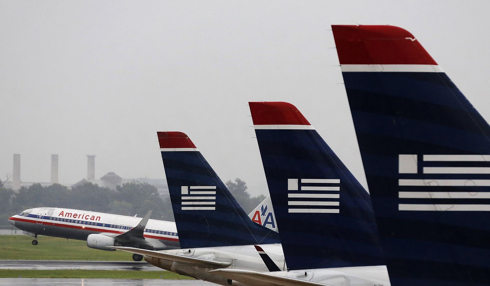 Un avión de American Airlines despegando en el aeropuerto Reagan de Washington con varias aeronaves de Us Airways en primer plano.