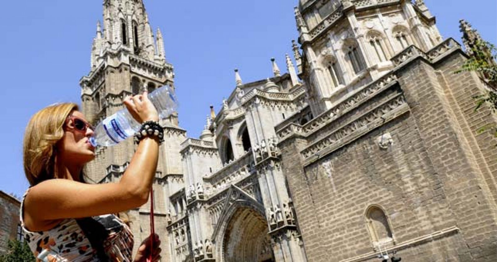 Mujer bebiendo agua frente a la catedral de Toledo.
