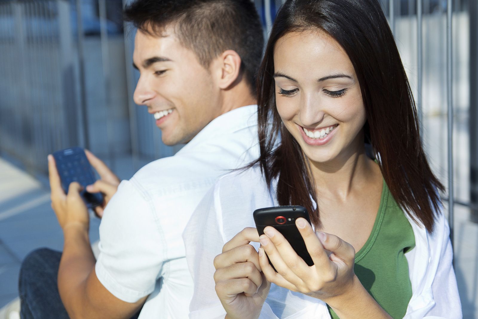 Una pareja joven y feliz con sus smartphones.