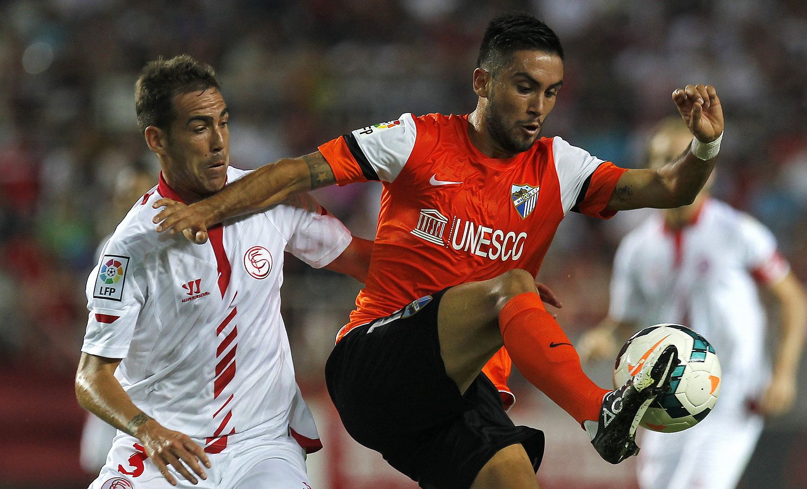 El defensa del Sevilla CF Fernando Navarro lucha el balón con el chileno Pedro Morales, del Málaga CF.