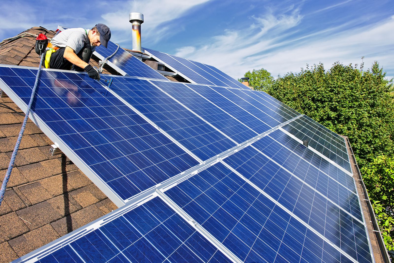 Un operario instala paneles solares en el tejado de una casa