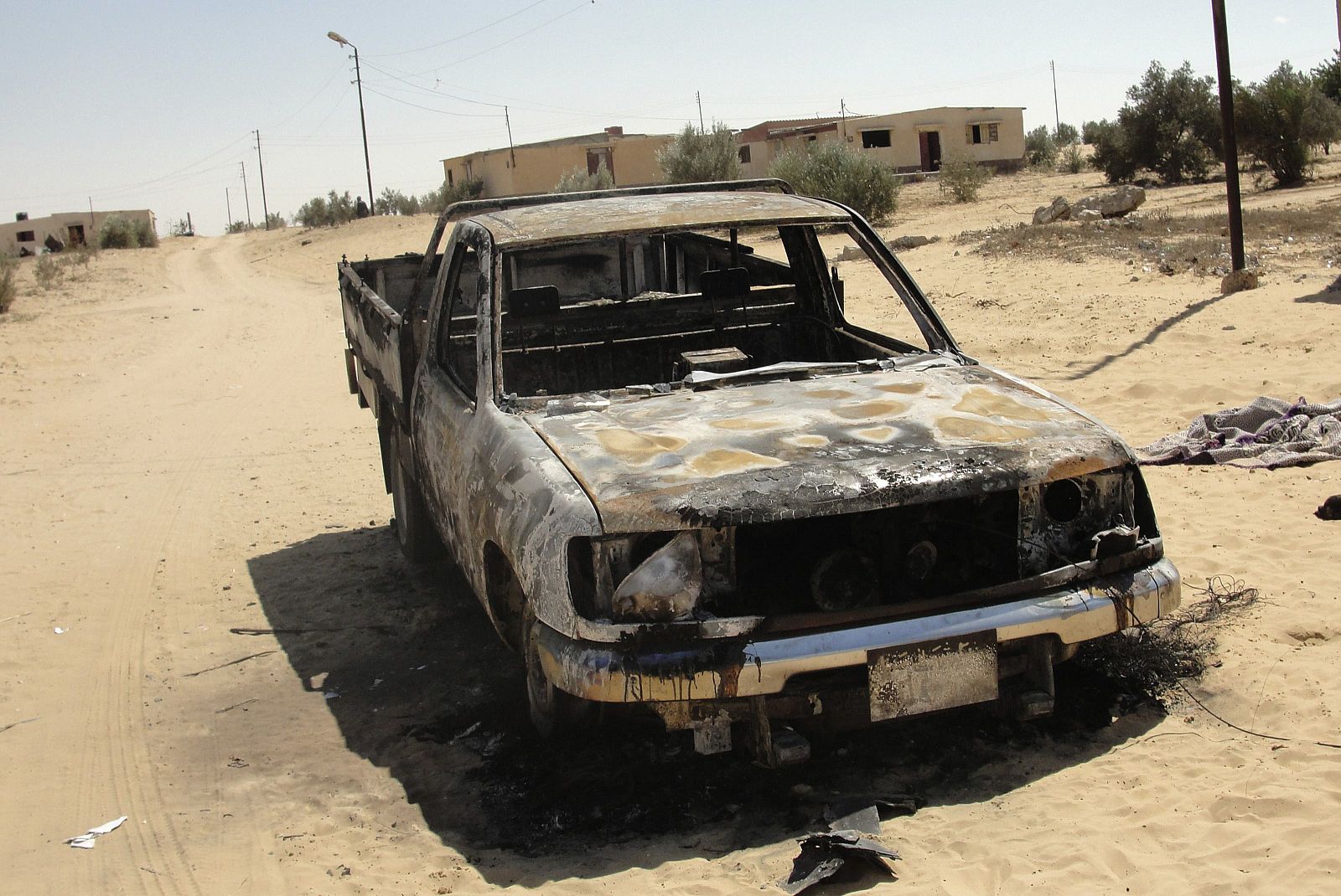 Un coche quemado cerca de la localidad de Sheij Zuweid, donde se han producido enfrentamientos entre el Ejército egipcio e islamistas