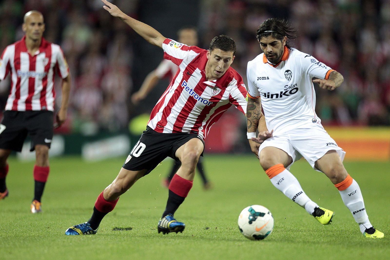 El centrocampista argentino del Valencia, Ever Banega, conduce el balón ante el acoso del jugador del Athletic de Bilbao, De Marcos.