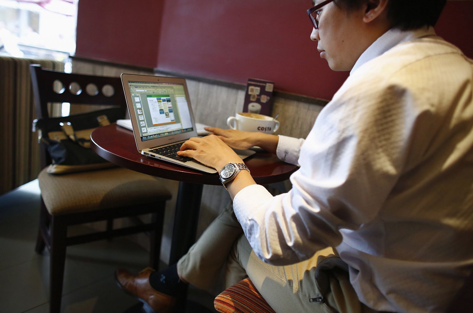 A man works on his computer inside a coffee shop in downtown Shanghai