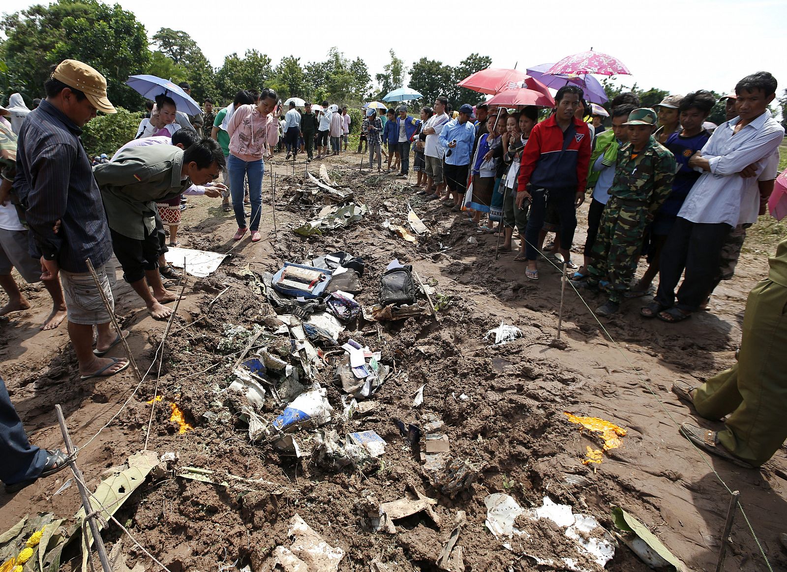 Varios lugareños observan una zona acotada donde permanecen varios objetos personales de los pasajeros del avión siniestrado en Laos