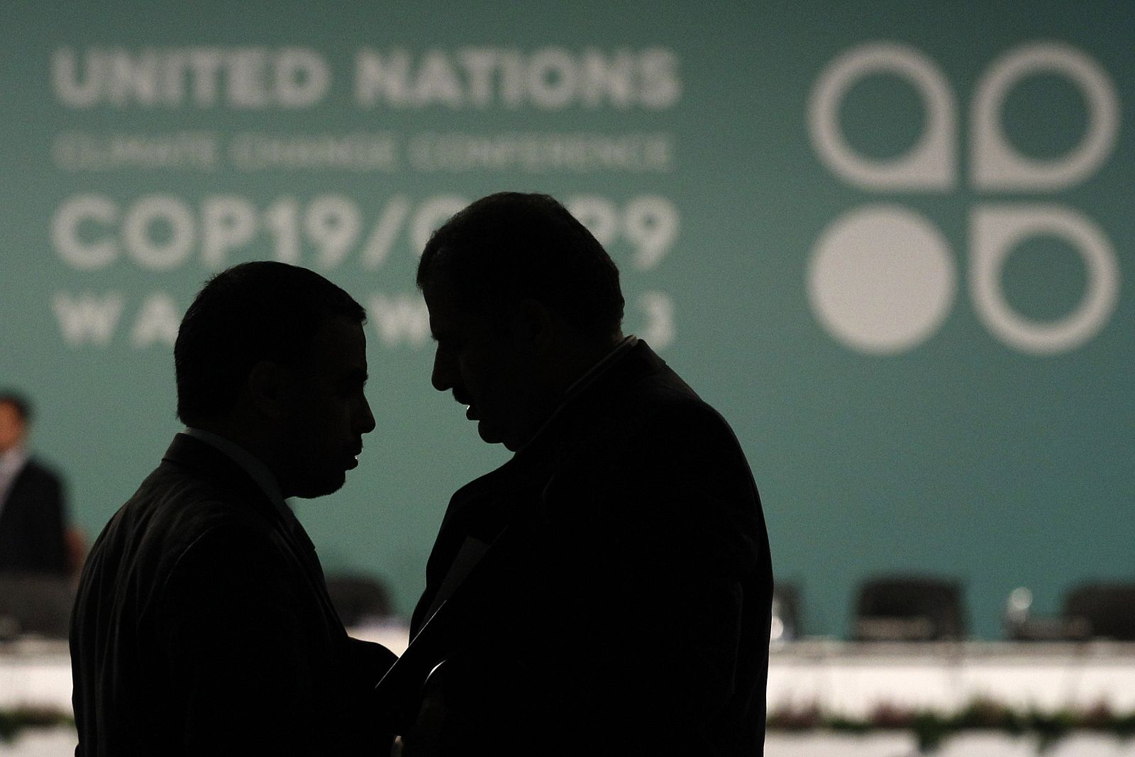 Dos delegados hablan durante una pausa de la sesión plenaria en el segundo día del COP19.