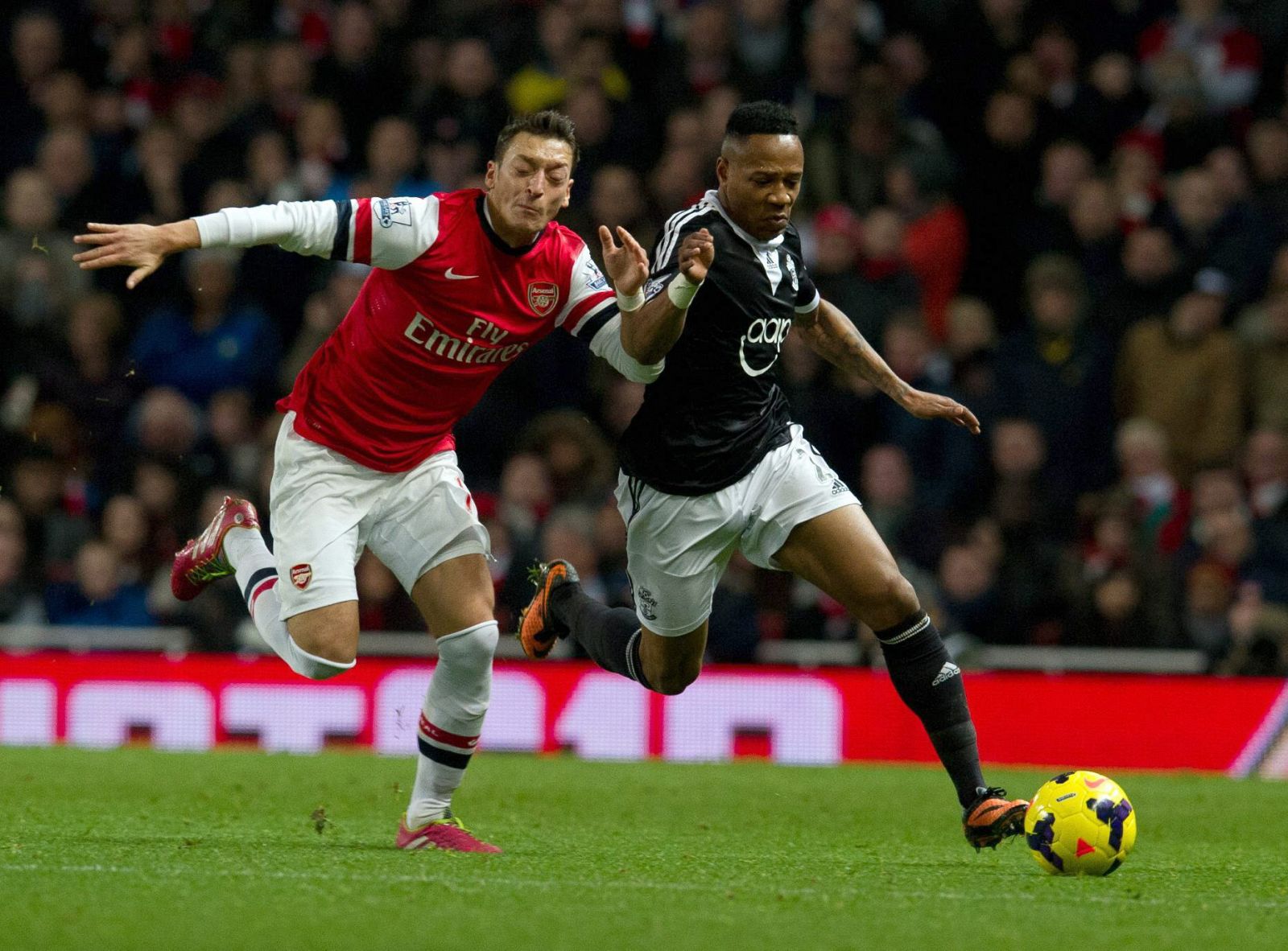 Mesut Özil, del Arsenal, disputa un balón con Nathan Clyde, del Southampton.