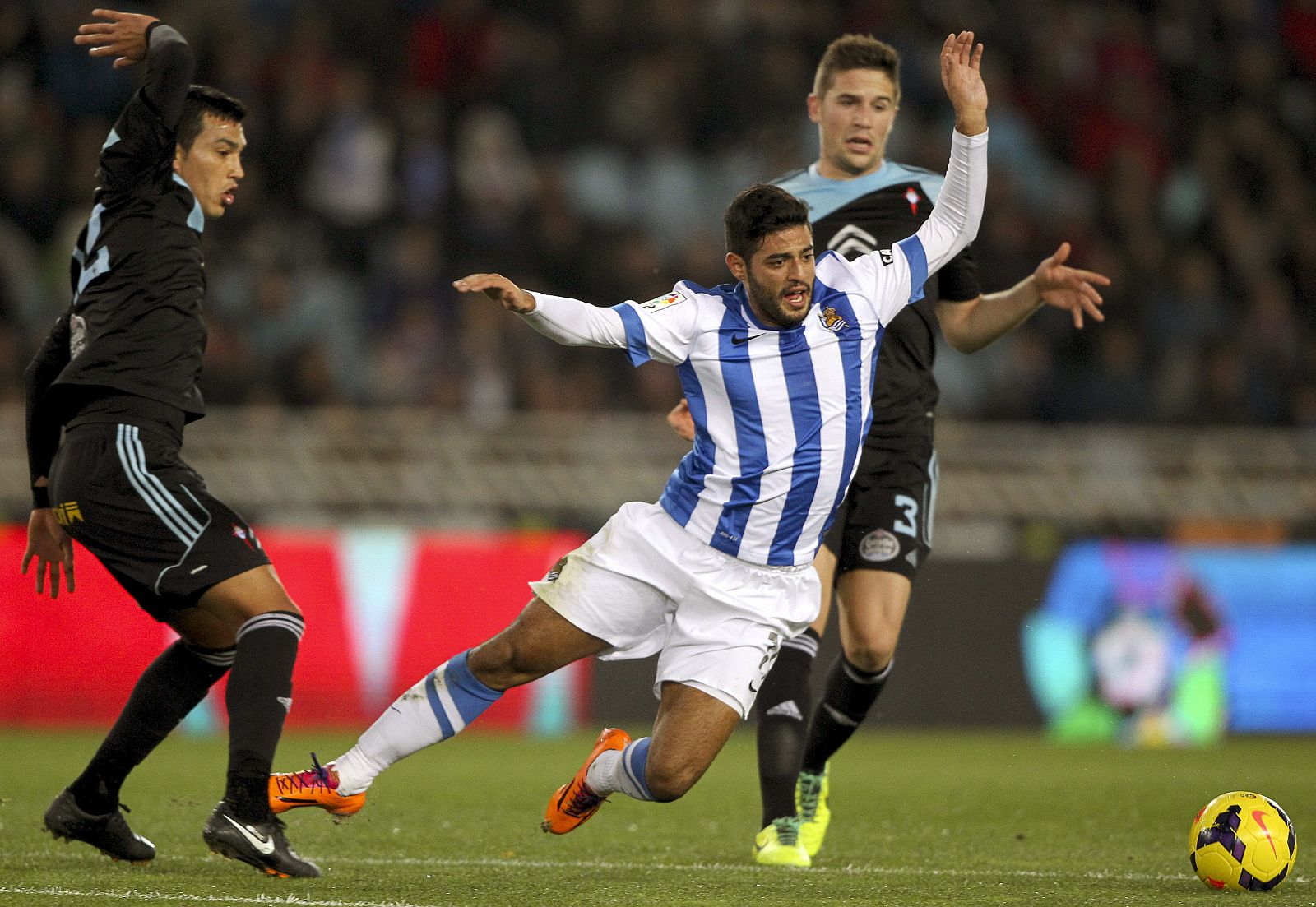 El delantero mexicano de la Real Sociedad, Carlos Vela (c) cae ante los defensas del Celta de Vigo, Gustavo Cabral (i) y Andreu Fontás