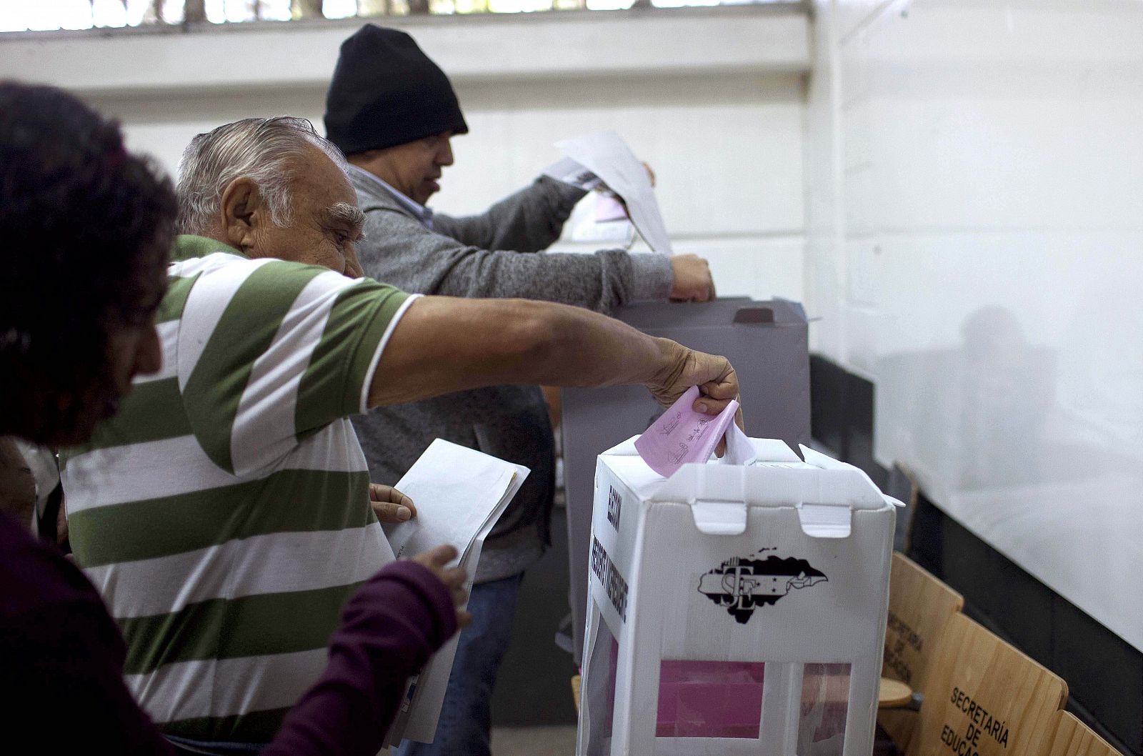 Dos hombres depositan su voto en un colegio electoral de Tegucigalpa, Honduras.