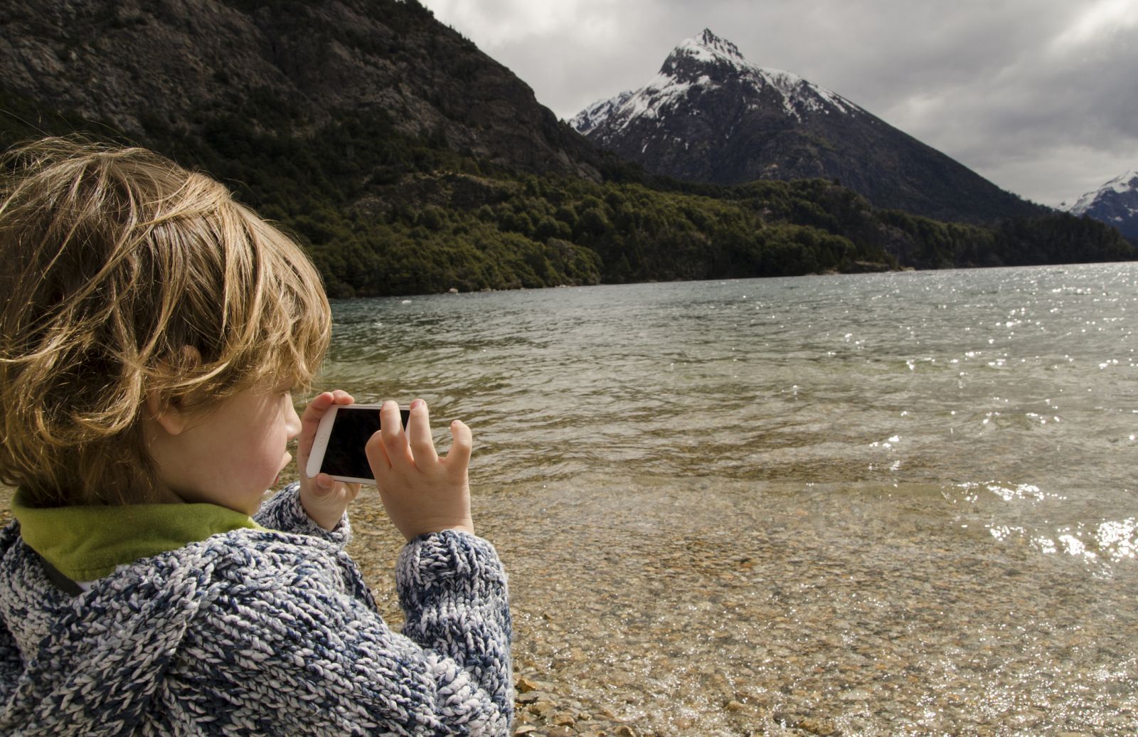 Un niño jugando con el móvil en medio de la naturaleza.
