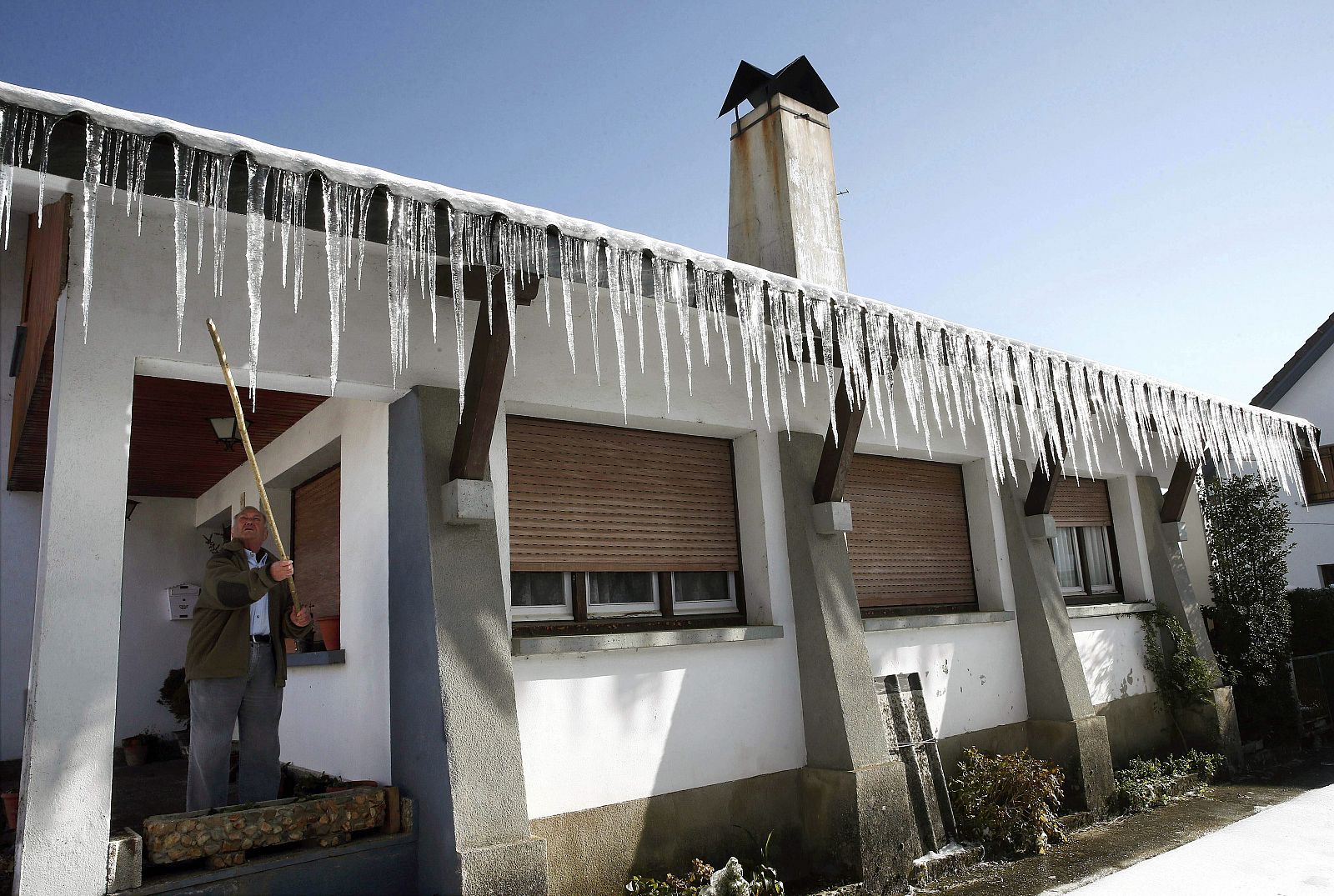 Un hombre observa los carámbanos de hielo sobre el tejado de su vivienda en Navarra
