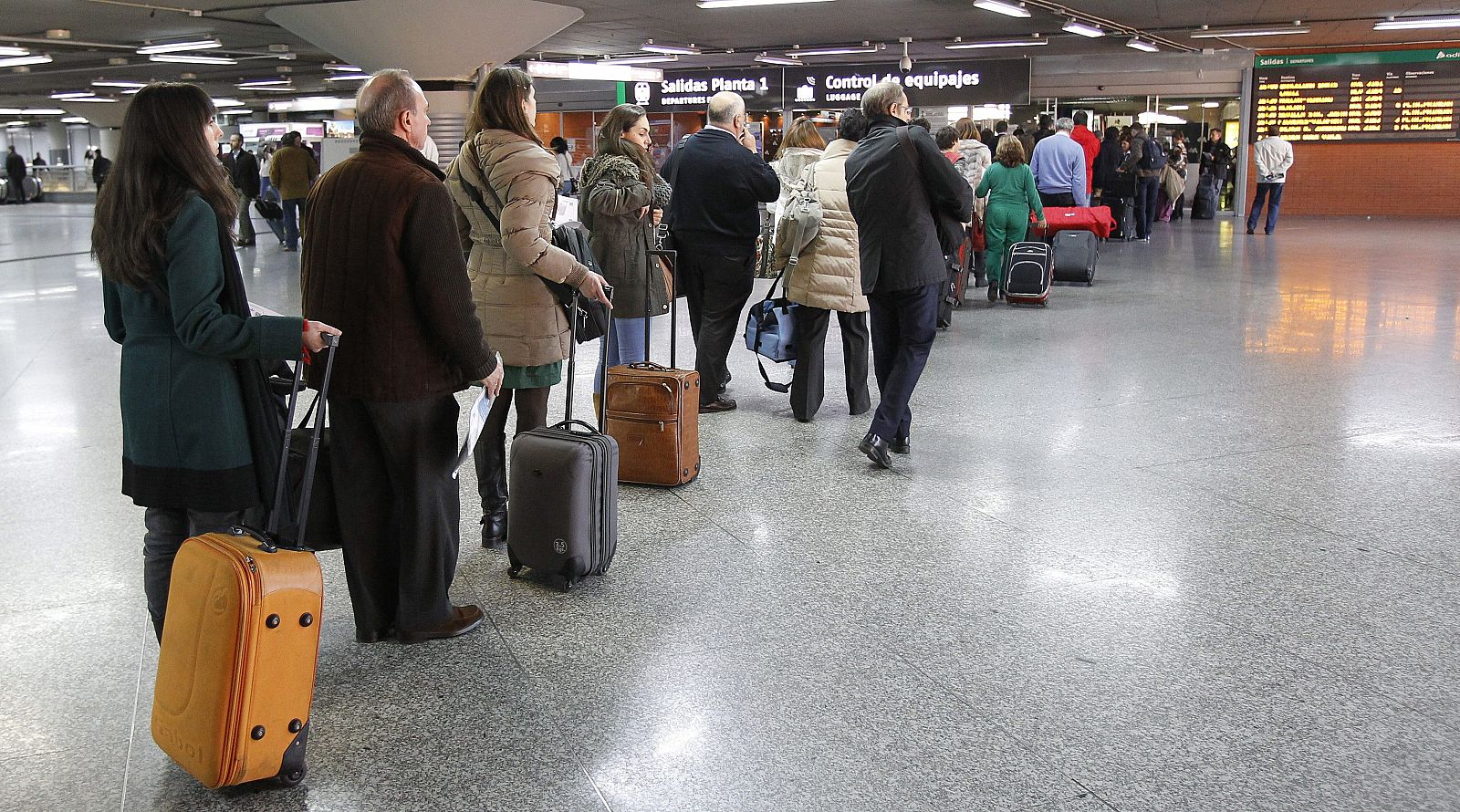 Varios viajeros hacen cola ante el control de equipajes en la estación de tren de Atocha, en Madrid