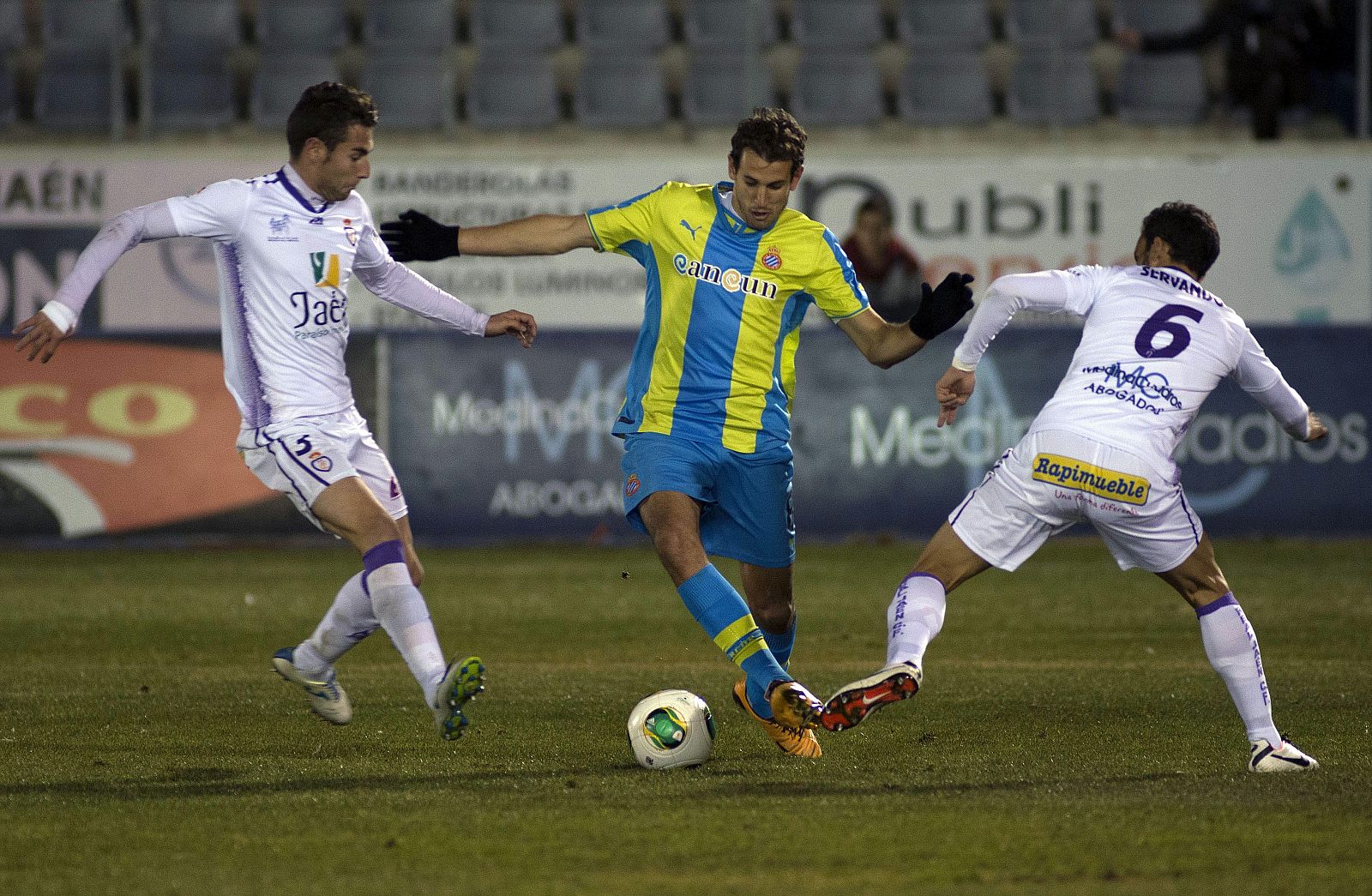 El delantero uruguayo del Espanyol, Cristhian Ricardo Stuani, intenta superar la defensa de los jugadores del Real Jaén, José Manuel Cruz y Servando.