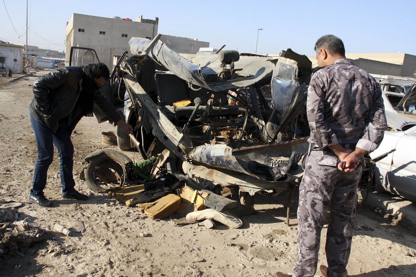 Un policía iraquí observa los restos de uno de los coches bomba que ha estallado en Bagdad