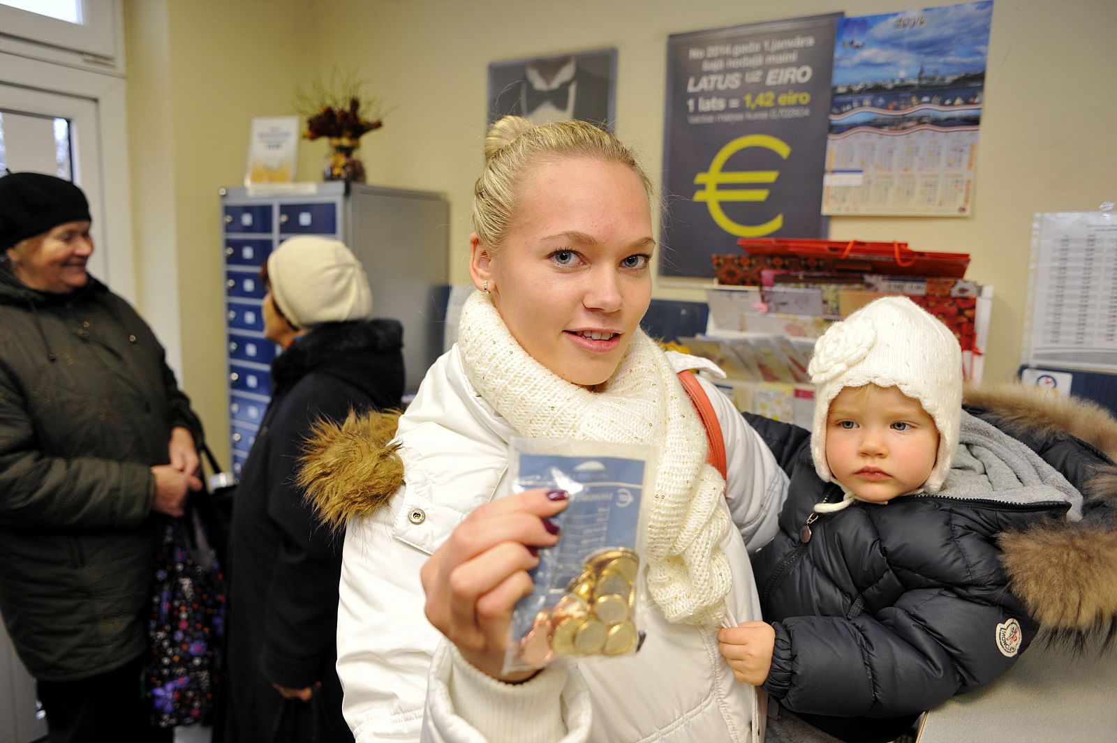 Linda Grabouska y su hija Jasmina muestran una bolsa con monedas de euro letonas