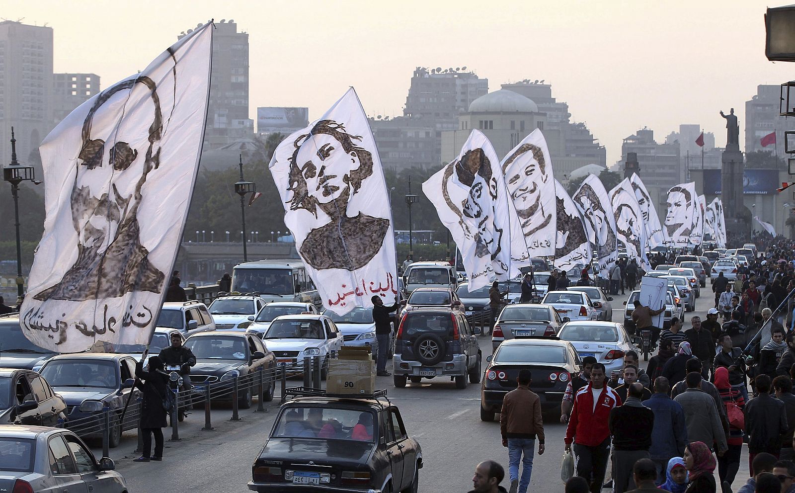 Varios manifestantes ondean banderas en las que aparecen los rostros de personas que fueron presuntamente asesinadas durante los disturbios acontecidos en 2011 contra el Consejo de Ministros, en los que al menos murieron 18 personas.