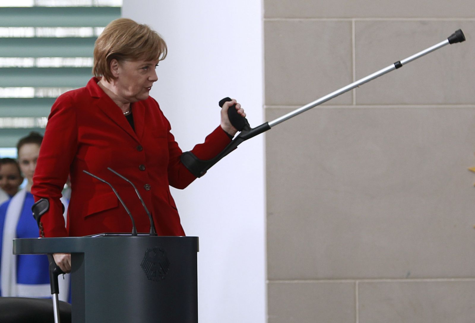 Angela Merkel hace un gesto con una muleta, tras fracturarse la pelvis