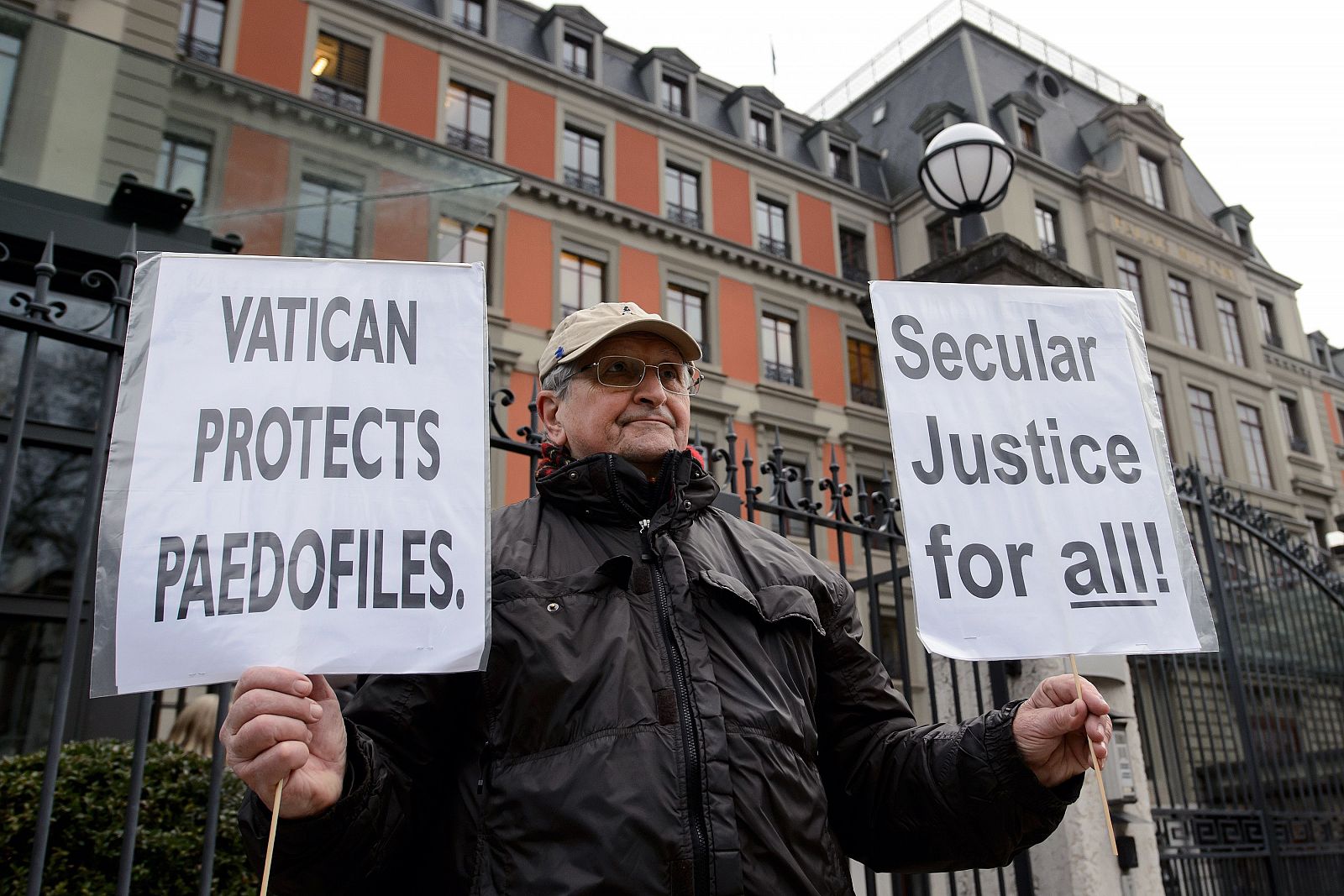 Un hombre protesta ante la sede del Alto Comisionado para los Derechos Humanos en Ginebra con dos carteles en los que culpa al Vaticano de proteger a los pederastas