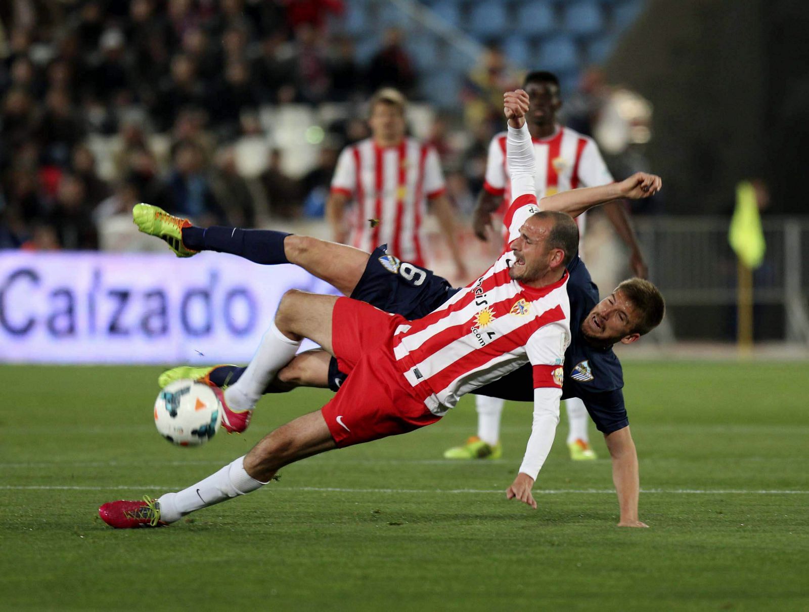 El jugador del Almería Soriano (delante) cae junto a Camacho, del Málaga.