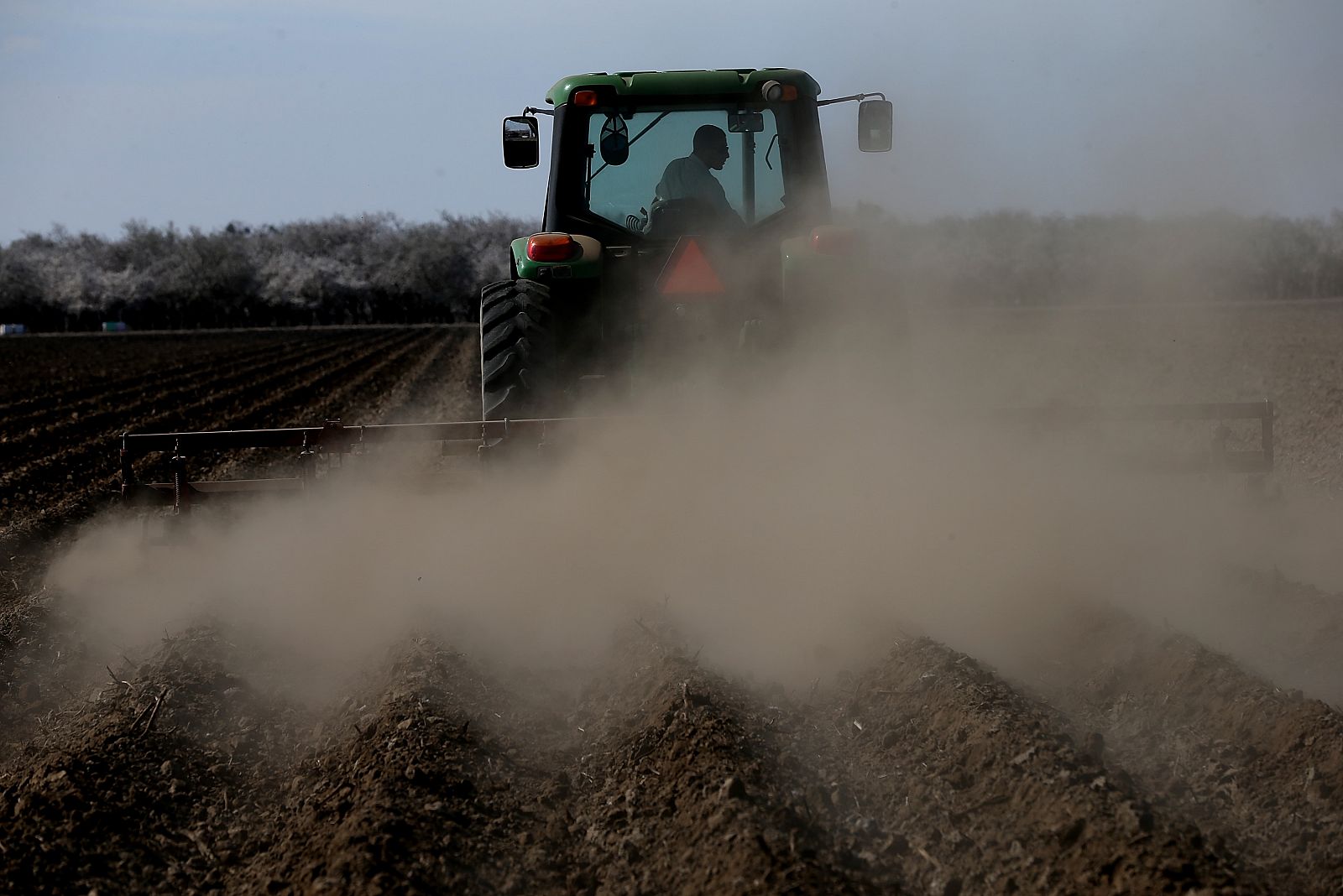 Un hombre ara el campo con su tractor