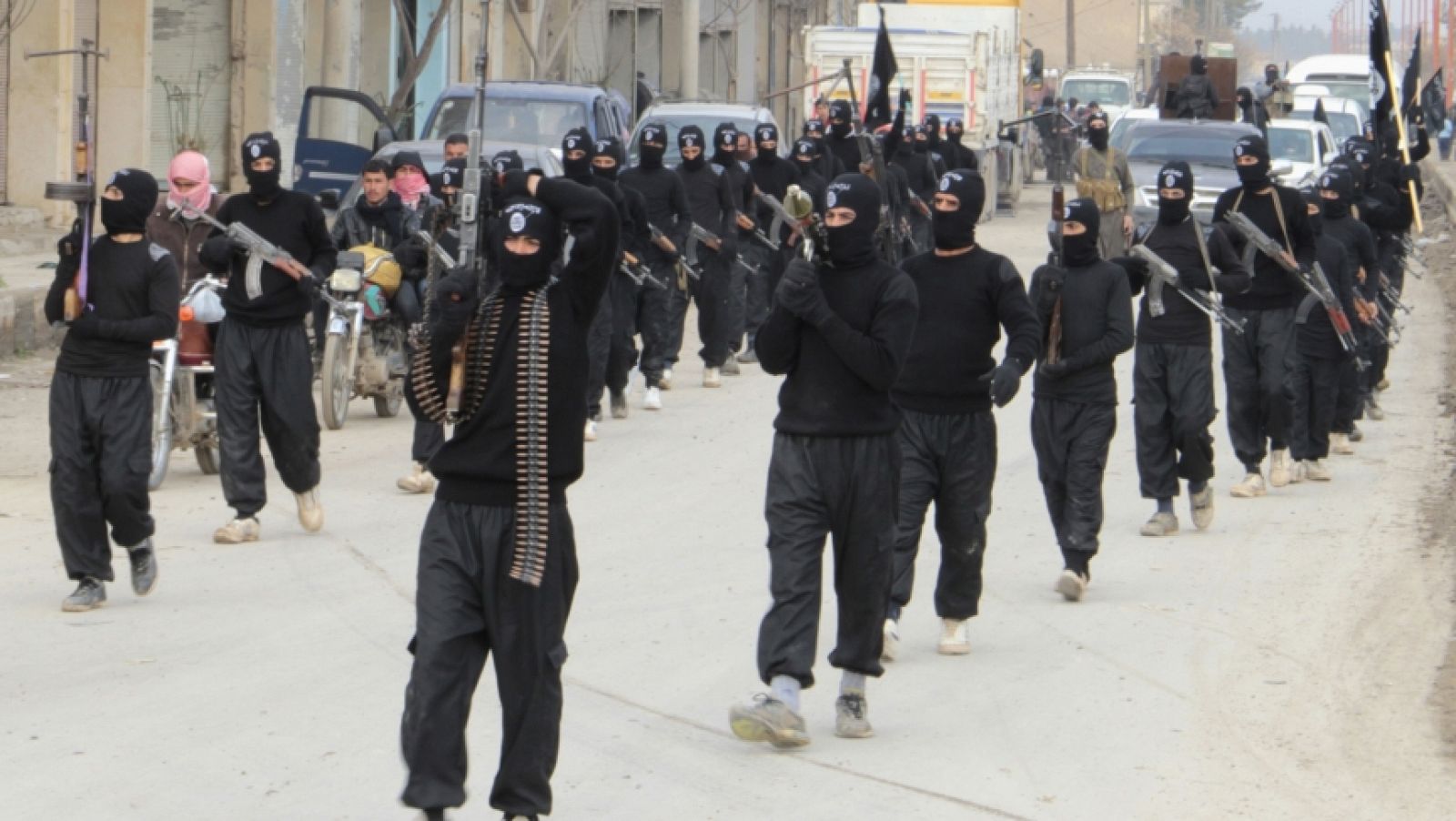 Combatientes de Al Qaeda ligados al Estado Islámico de Irak y el Levante levantan sus armas durante un desfilo en Tel Abyad, Siria, cerca de la frontera con Turquía.
