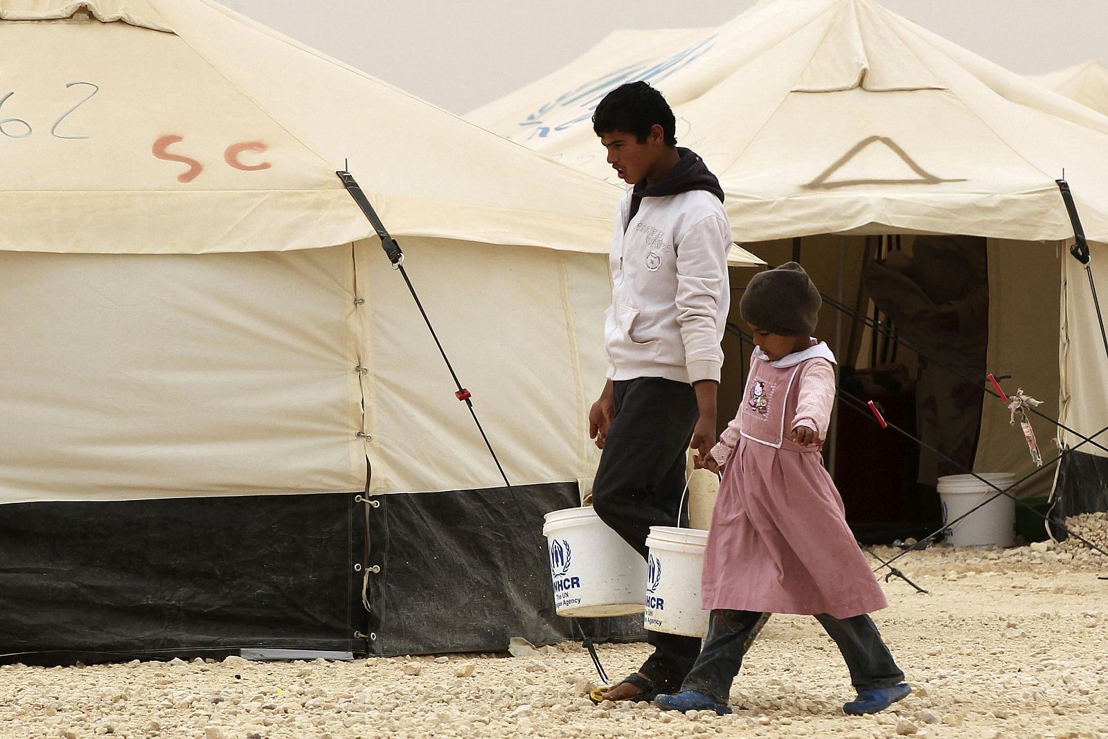 Dos niños del campamento de refugiados de Alzaatri, en Jordania, transportando cubos de agua