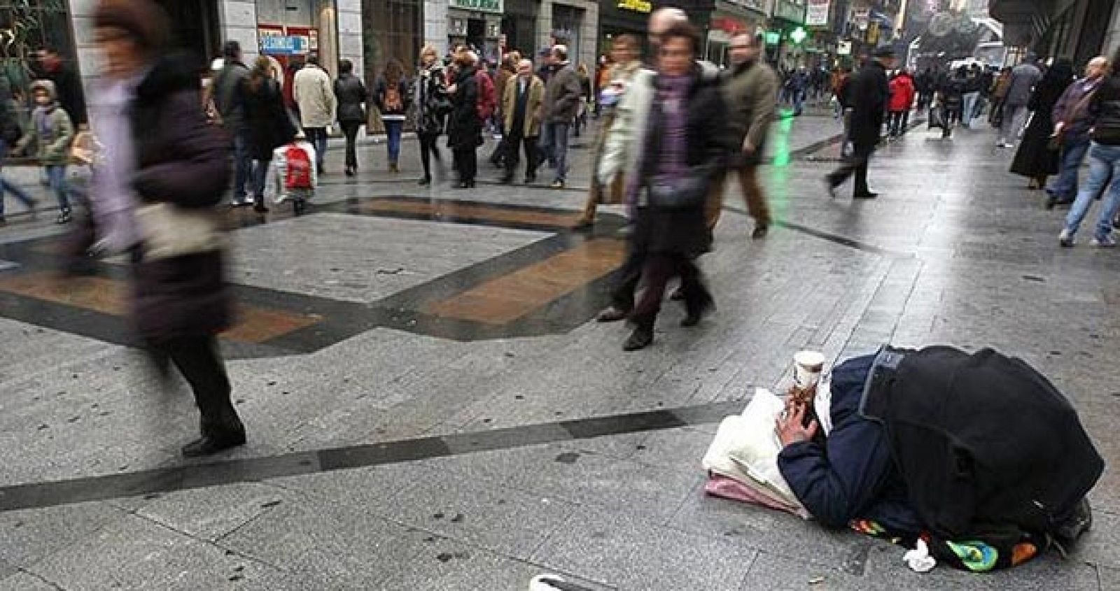 Un mendigo pide limosna en la calle Preciados de Madrid