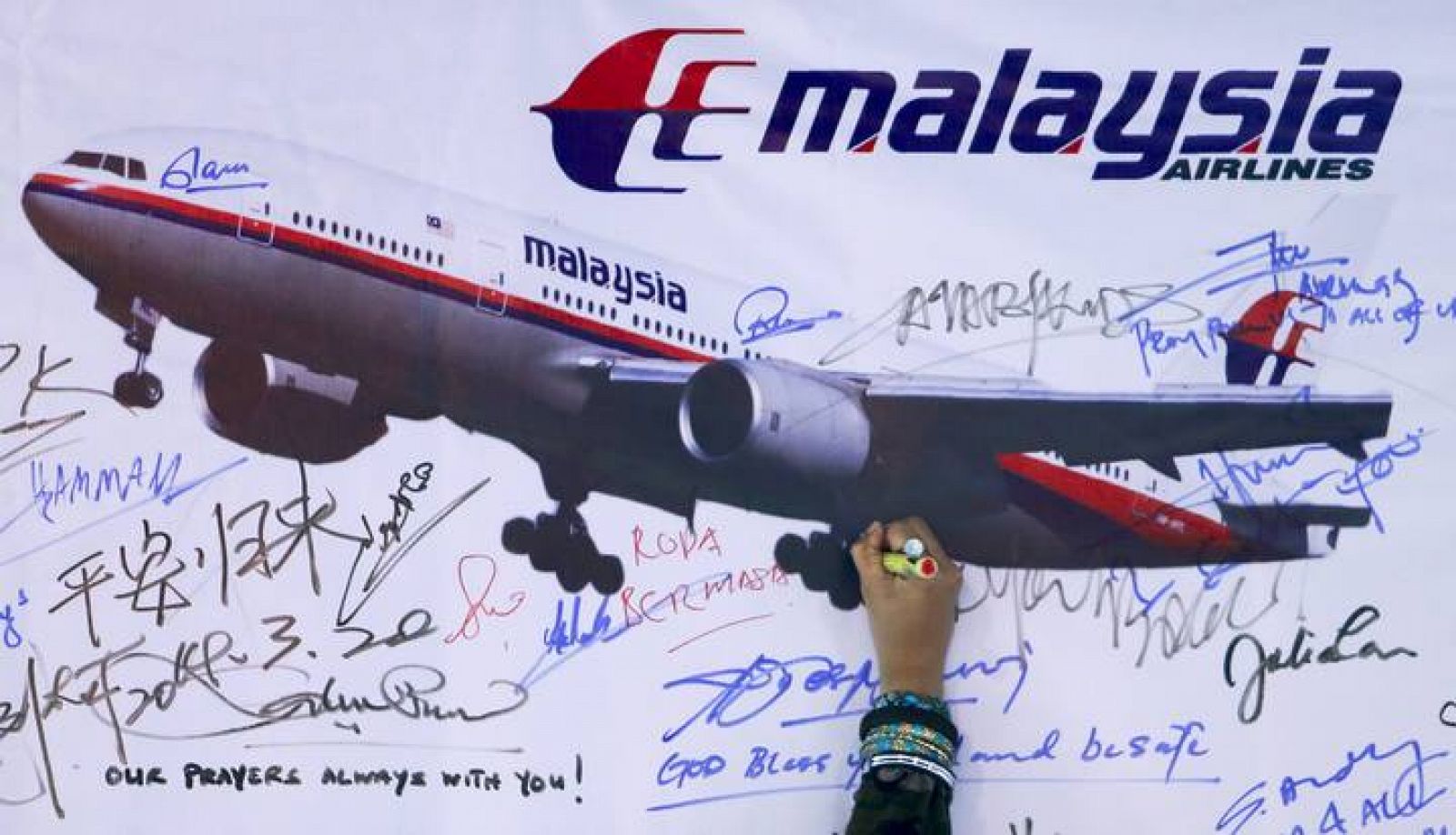 Un mujer escribe un mensaje en recuerdo del vuelo MH370 de Malaysia Airlines