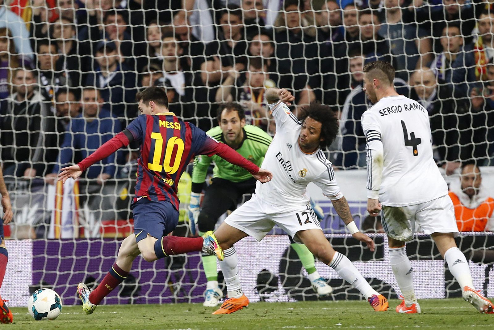 El delantero argentino del FC Barcelona Lionel Andrés Messi lanza para marcar gol ante la defensa de los jugadores del Real Madrid, el brasileño Marcelo Vieira y Sergio Ramos.